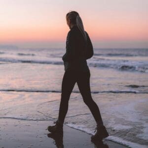 Eine Frau läuft in der Dämmerung am Meer