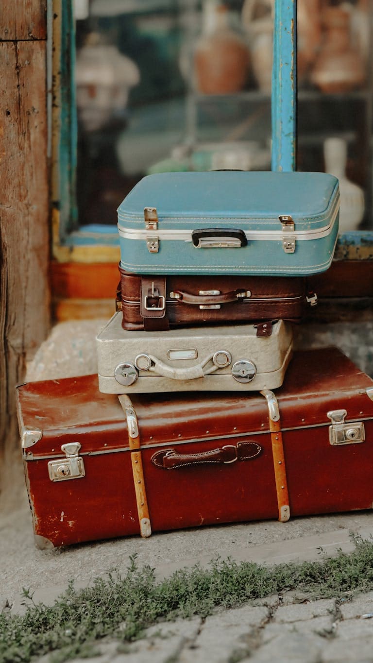 A stack of vintage suitcases by an old-fashioned shop entrance, perfect for travel themes.